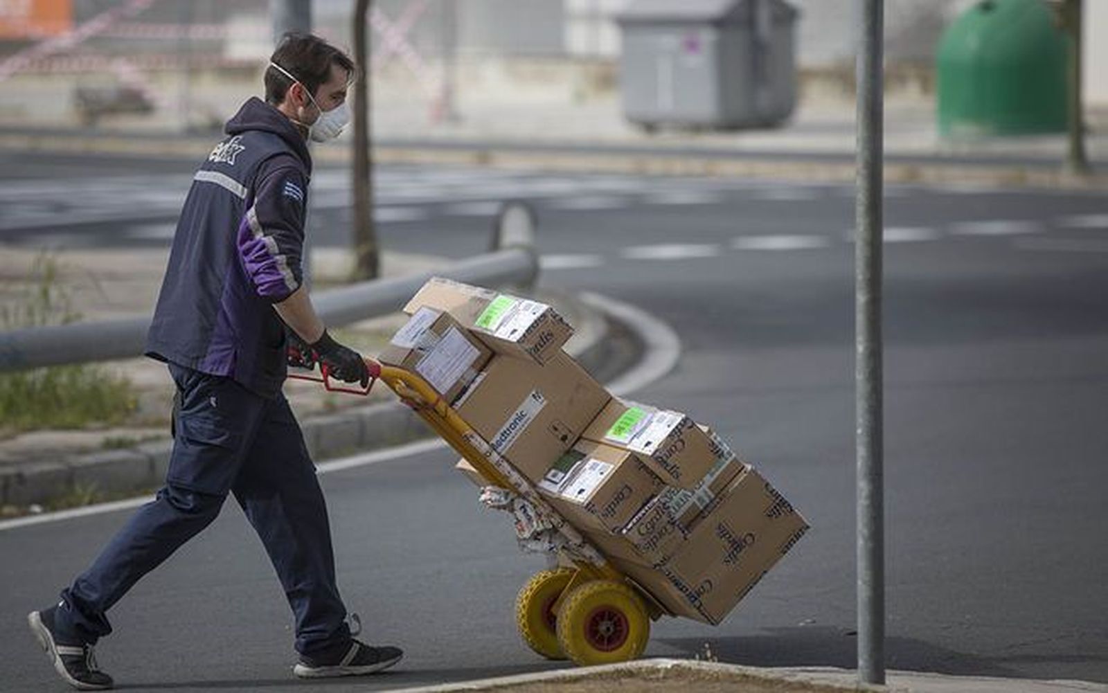 Un repartidor carga con varios paquetes. Foto EP