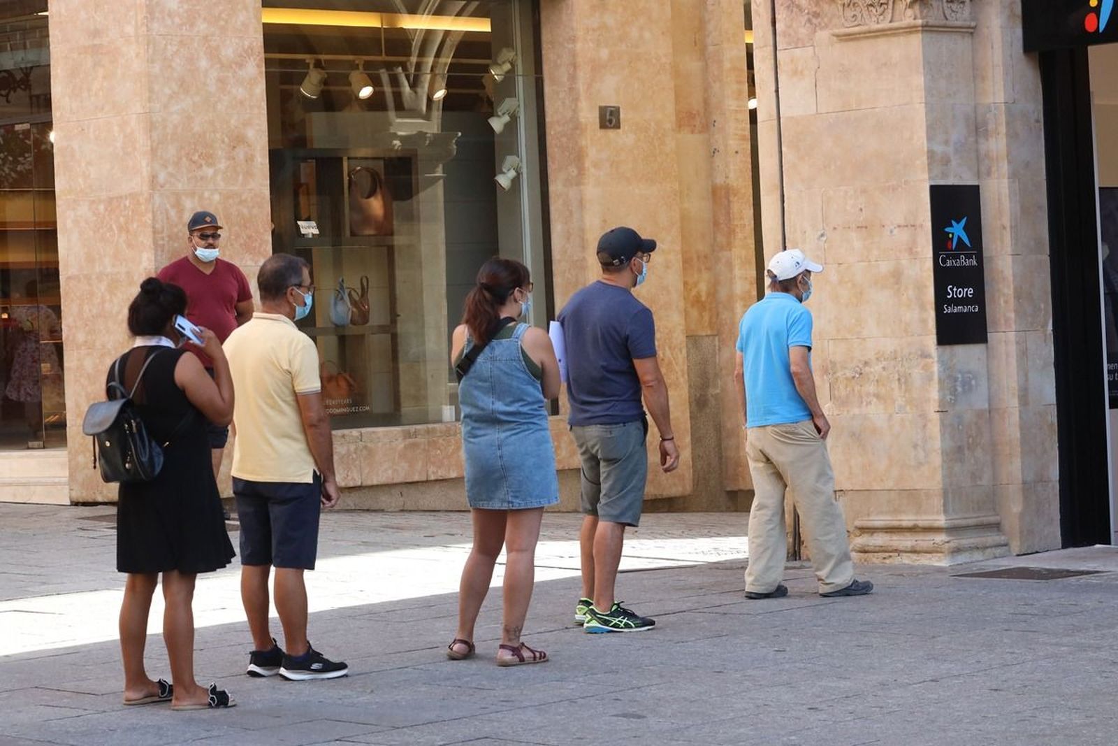 Grupo de personas hacen cola en un banco