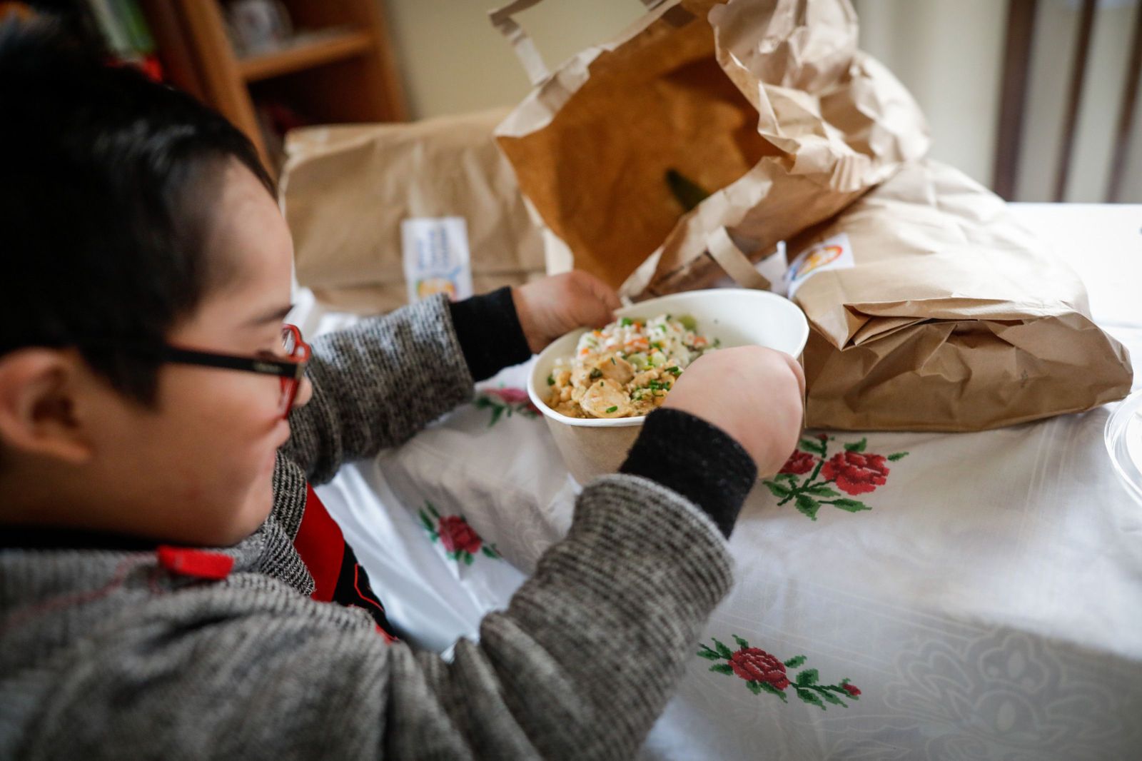 Un niño durante la comida en su casa del barrio madrileño de Carabanchel abre la tapa de un plato del menú de la ONG del chef José Andrés, a 14 de abril de 2020.