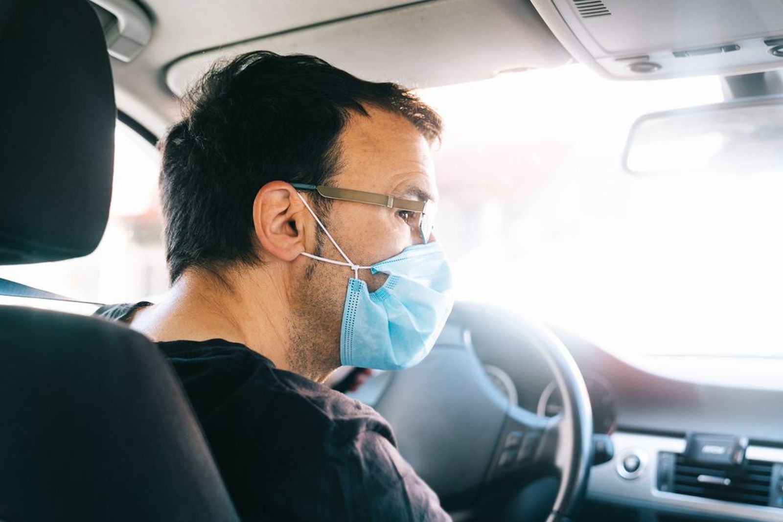 Hombre con mascarilla por la alergia al volante