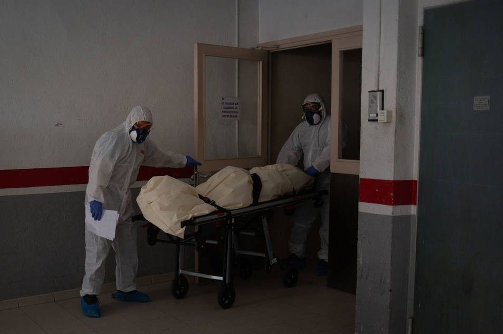 Dos operarios funerarios trabajando con equipos de protección