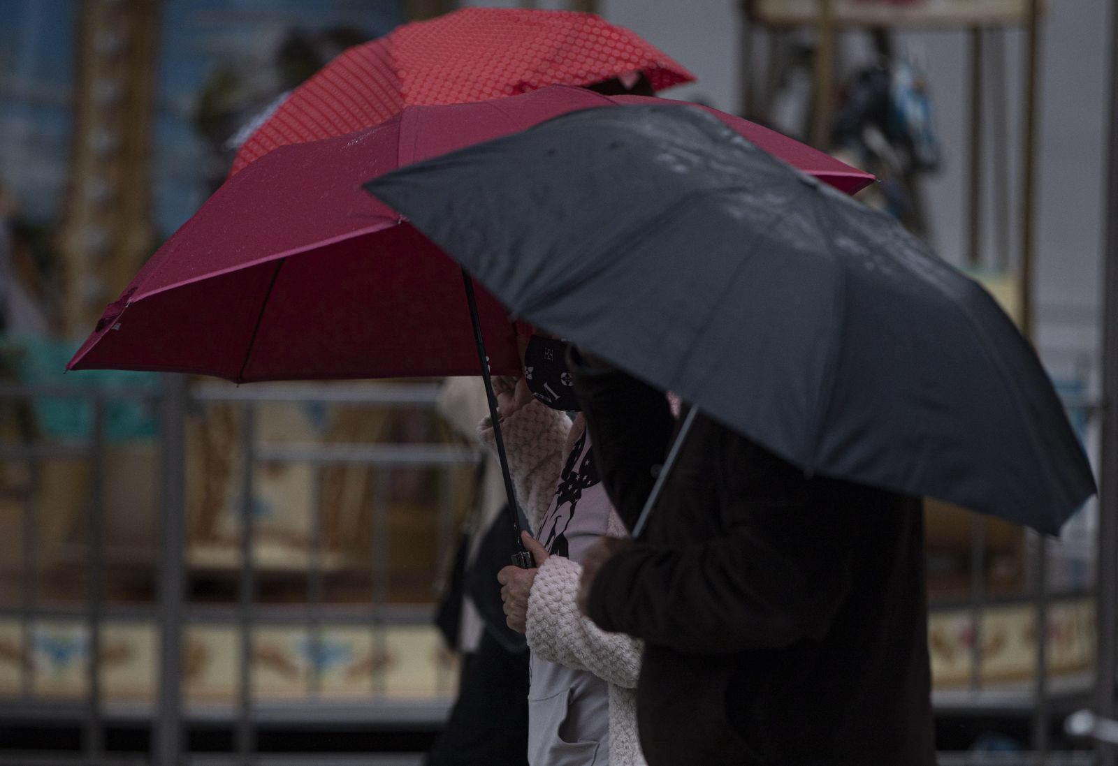 Mujeres con paraguas se protegen del viento y la lluvia. Foto de archivo