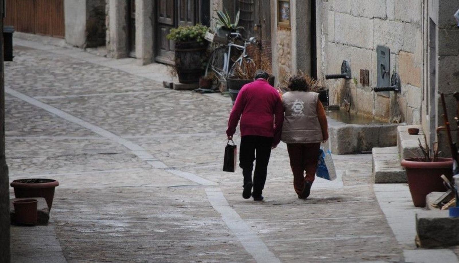 Dos personas pasean por la calle principal de un pueblo Dos personas pasean por la calle principal de un pueblo