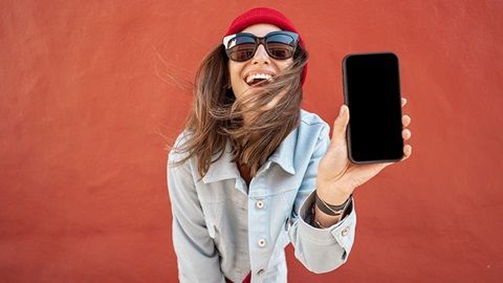 Una chica sujeta un teléfono móvil. OCU