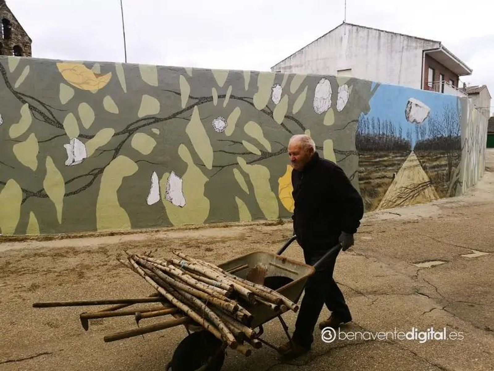 Un vecino de Burganes conduce el carretillo delante del mural. Foto: Benaventedigital