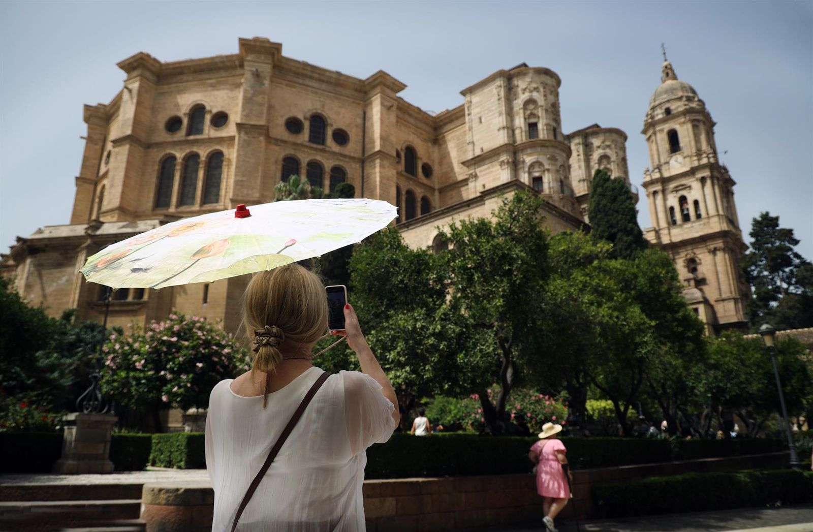 Una señora con un paraguas fotografía la Catedral durante la ola de calor que estos días azota la capital a 19 de julio e 2023 en Málaga, Andalucía. La Agencia Estatal de Meteorología (Aemet) ha activado para este mi