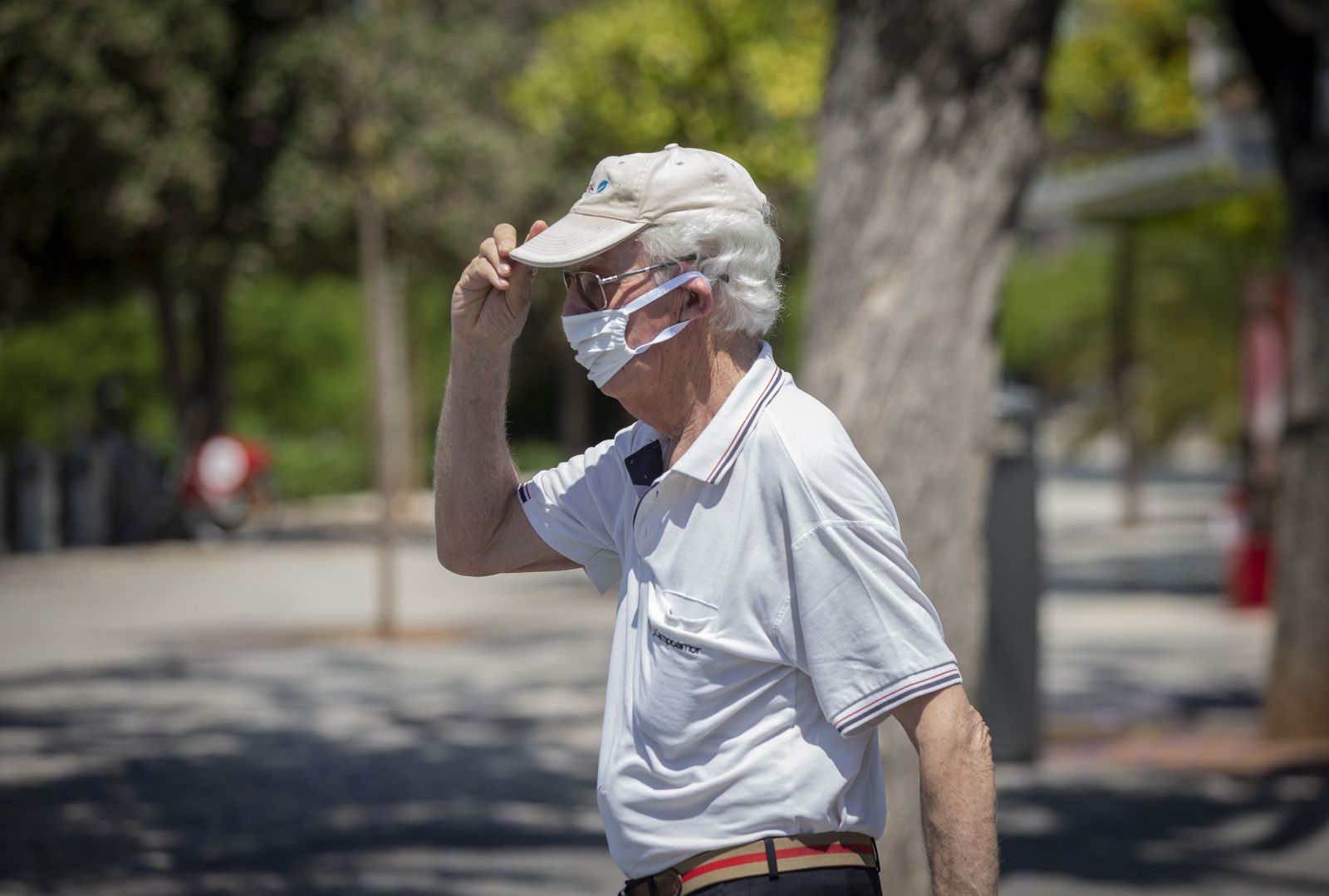 Un hombre con mascarilla y gafas de sol se coloca una gorra durante un "episodio de altas temperaturas". Según la calificación de la  Agencia Estatal de Meteorología (AEMET). En Sevilla,(Andalucía