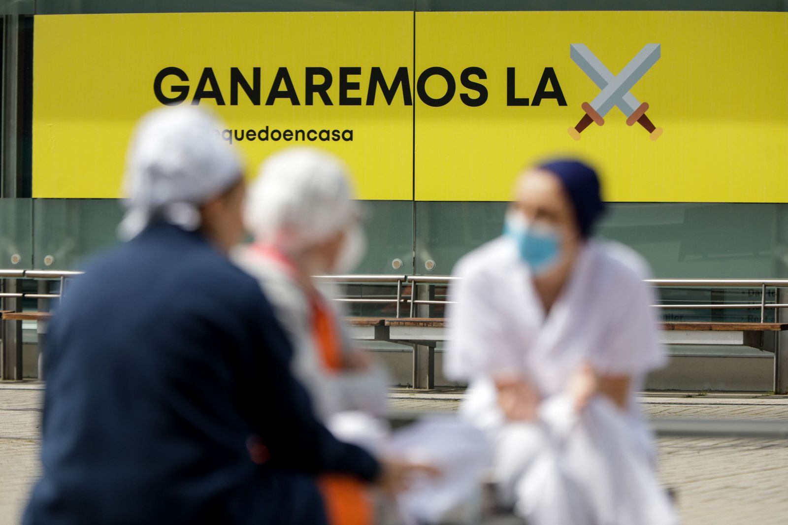 Sanitarios junto a un cartel en el que se lee 'Ganaremos la batalla' en el hospital de campaña de IFEMA, en el que los pacientes de coronavirus son ahora atendidos únicamente en el Pabellón 9 tras