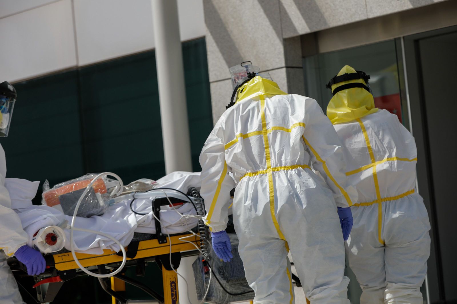 Varios sanitarios trasladan a un paciente desde el interior de la unidad móvil del SUMMA hasta la entrada del Hospital Puerta de Hierro tras haberle trasladado anteriormente desde la UVI del hospital