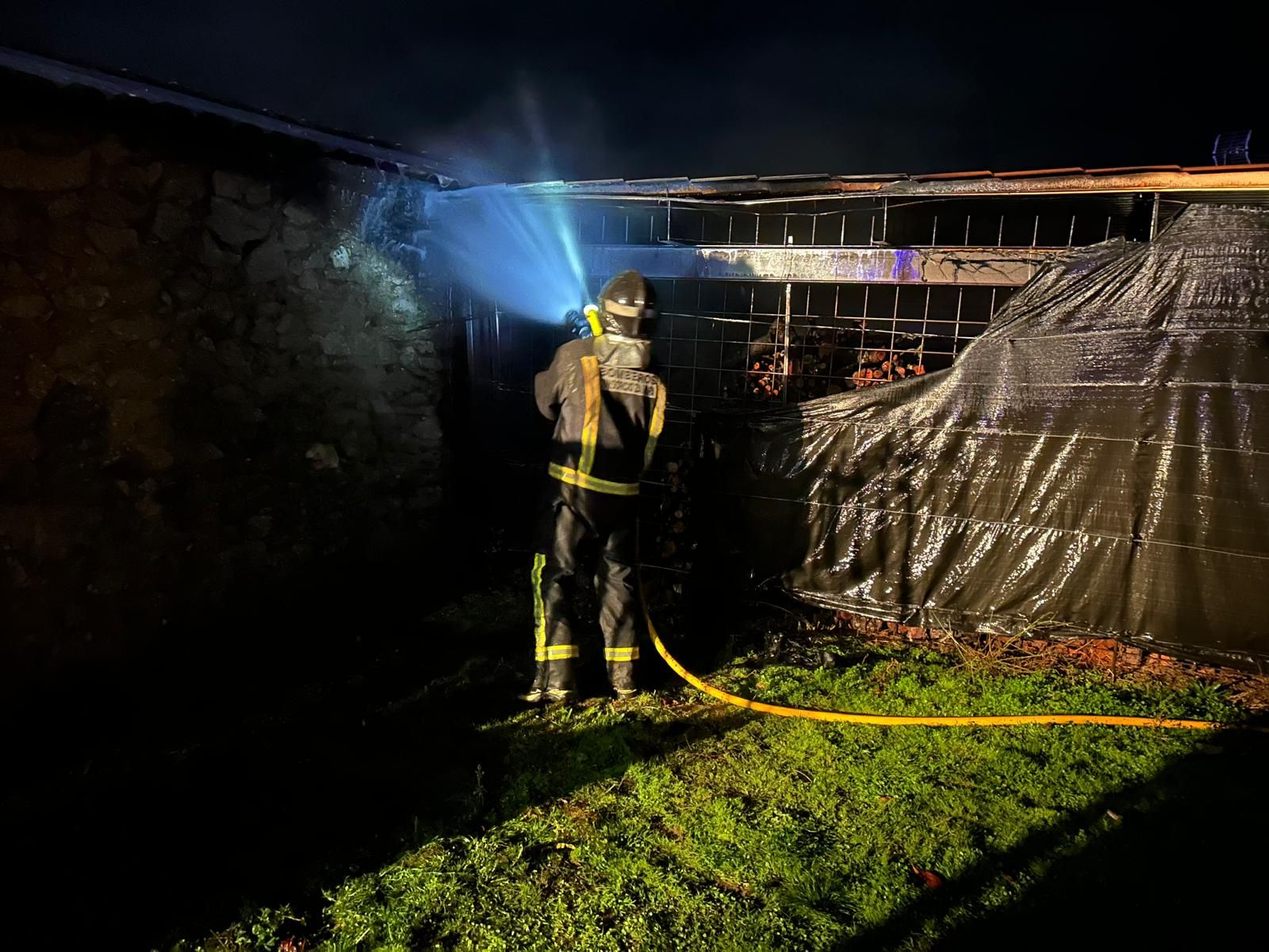 Un bombero sofocando las llamas en la zona anexa al garaje