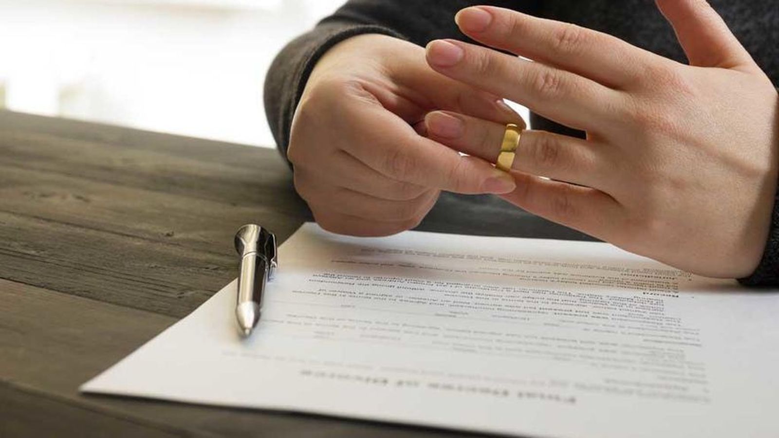 Una persona se retira la alianza tras firmar los papeles del divorcio