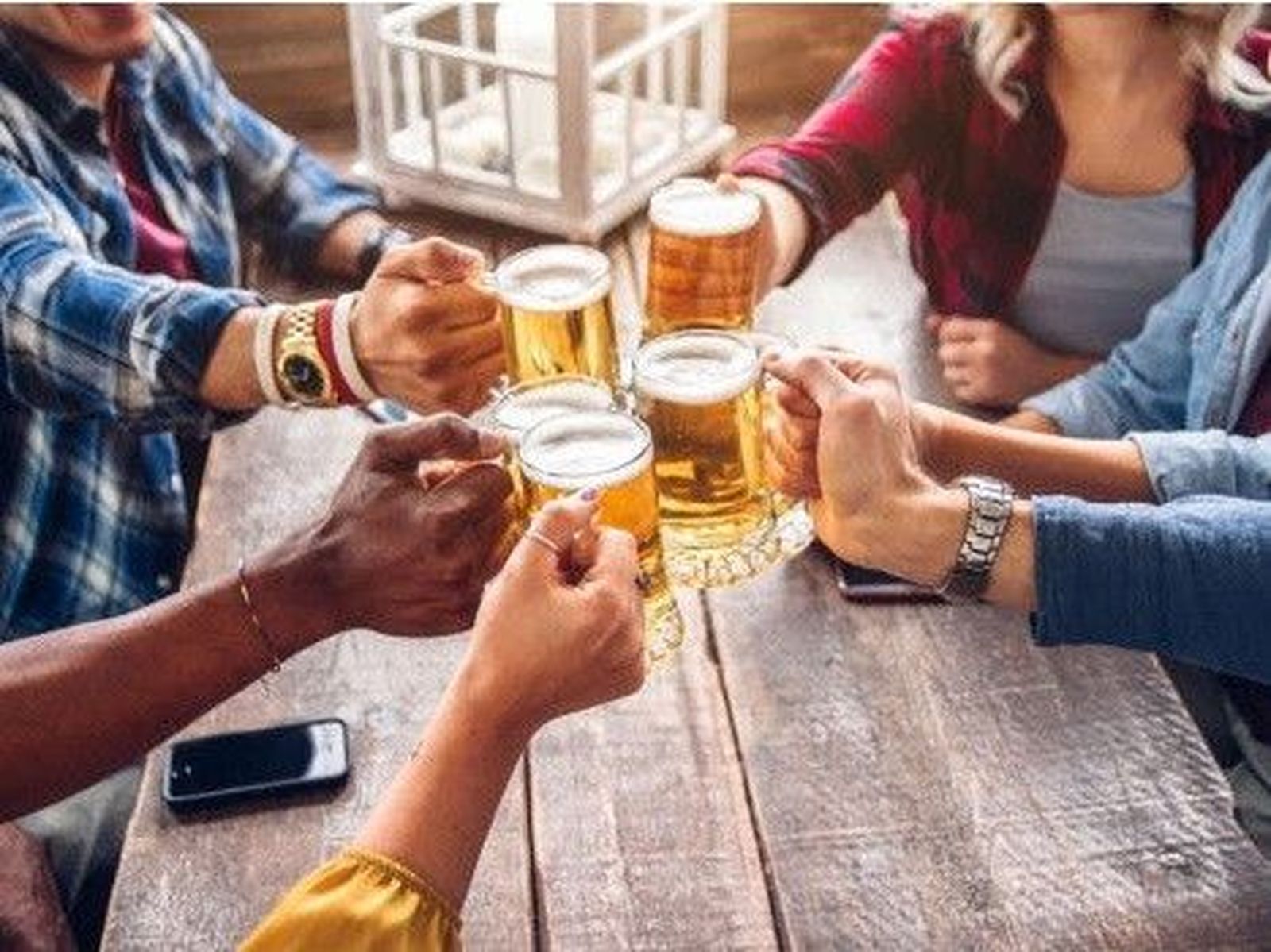 Varias personas brindan con cerveza.