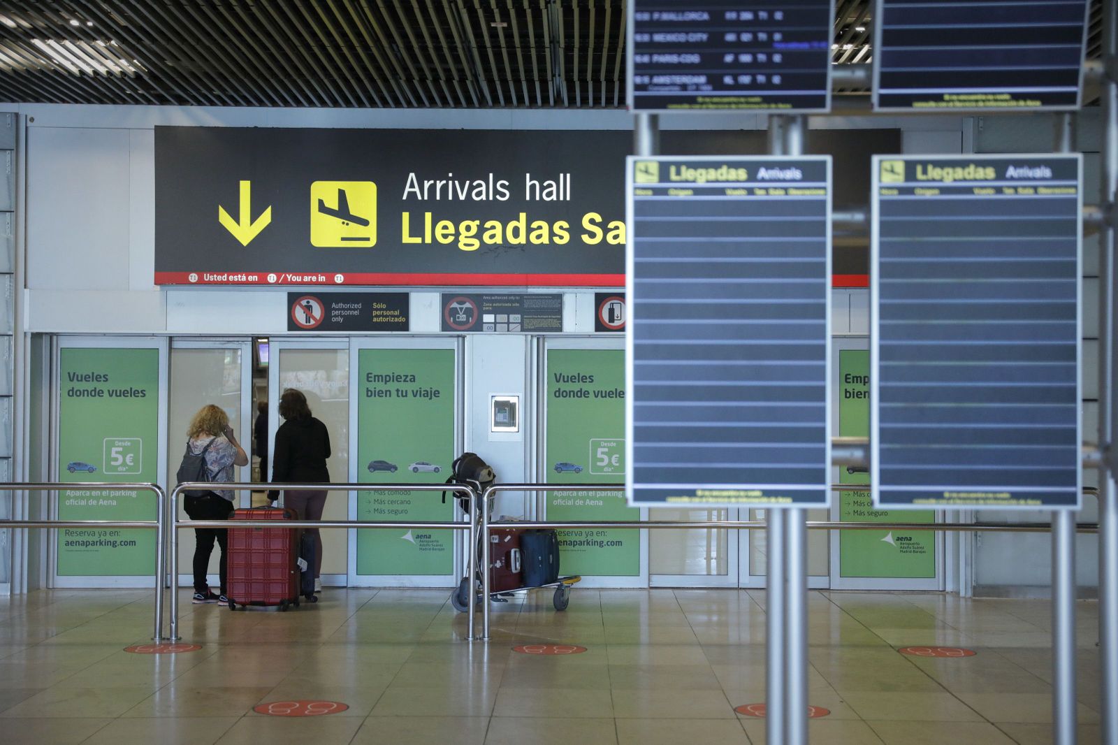 Dos personas con una maleta, frente a una de las salidas de la sala de llegadas de la Terminal 1 del Aeropuerto de Barajas, en Madrid(España) a 4 de julio de 2020.