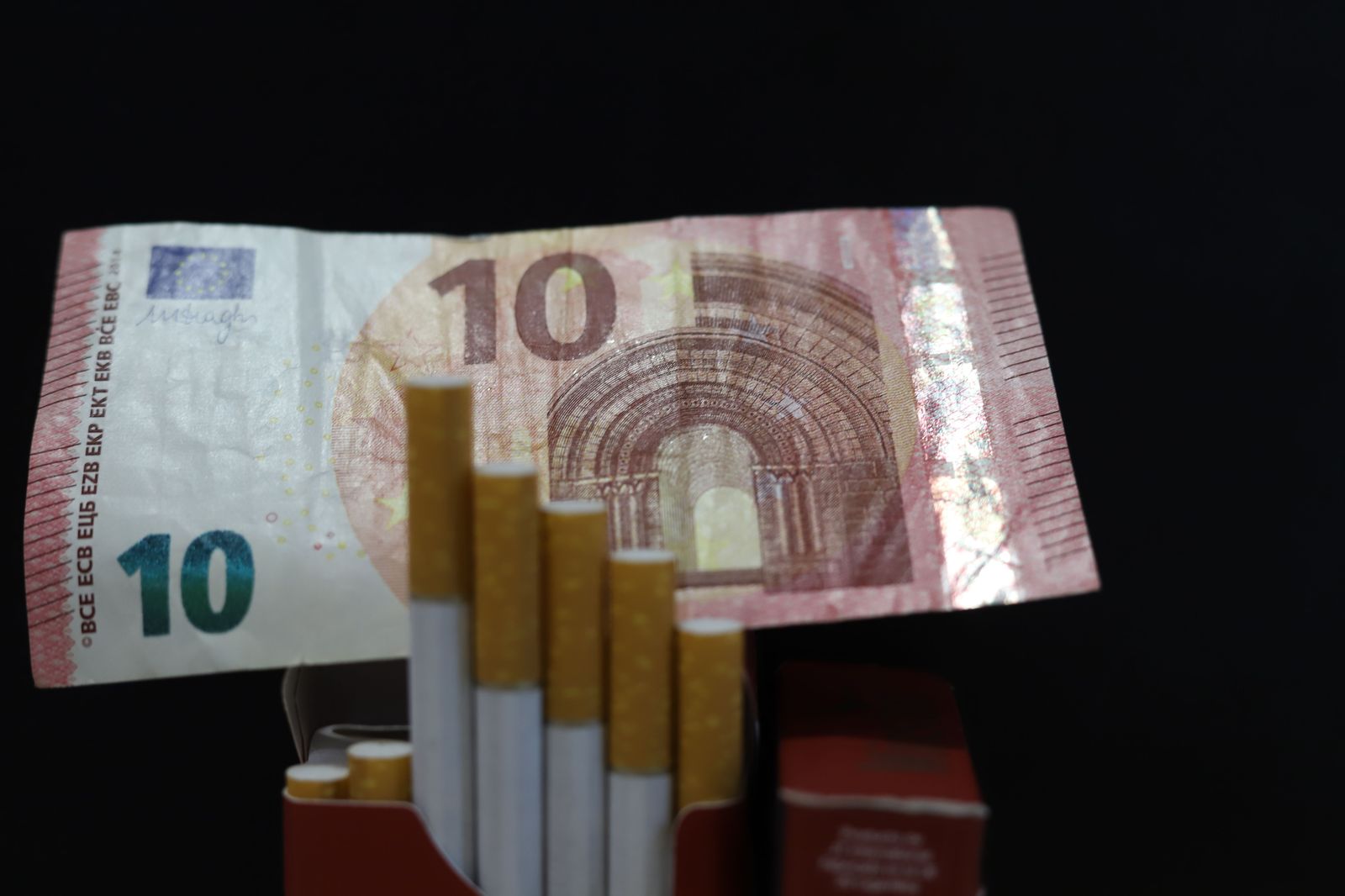Una cajetilla de cigarrillos junto a un billete de diez euros
