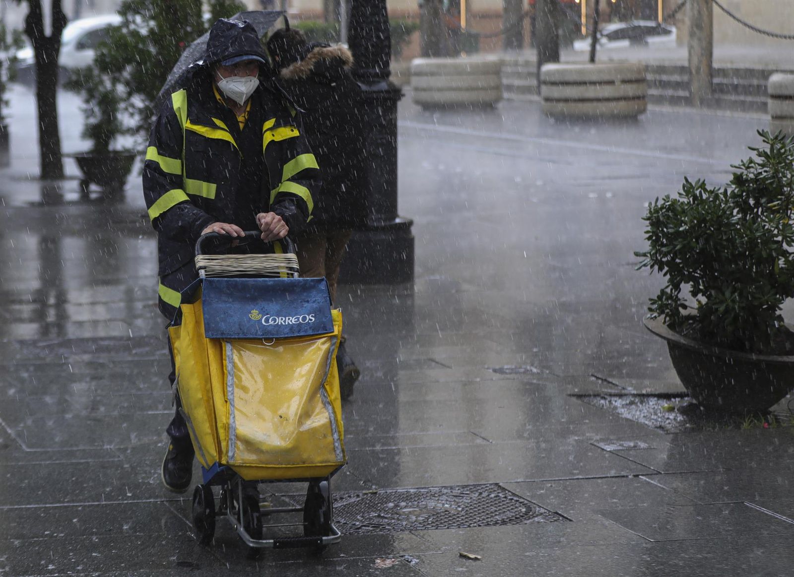 Un repartidor de correos trabaja bajo la lluvia