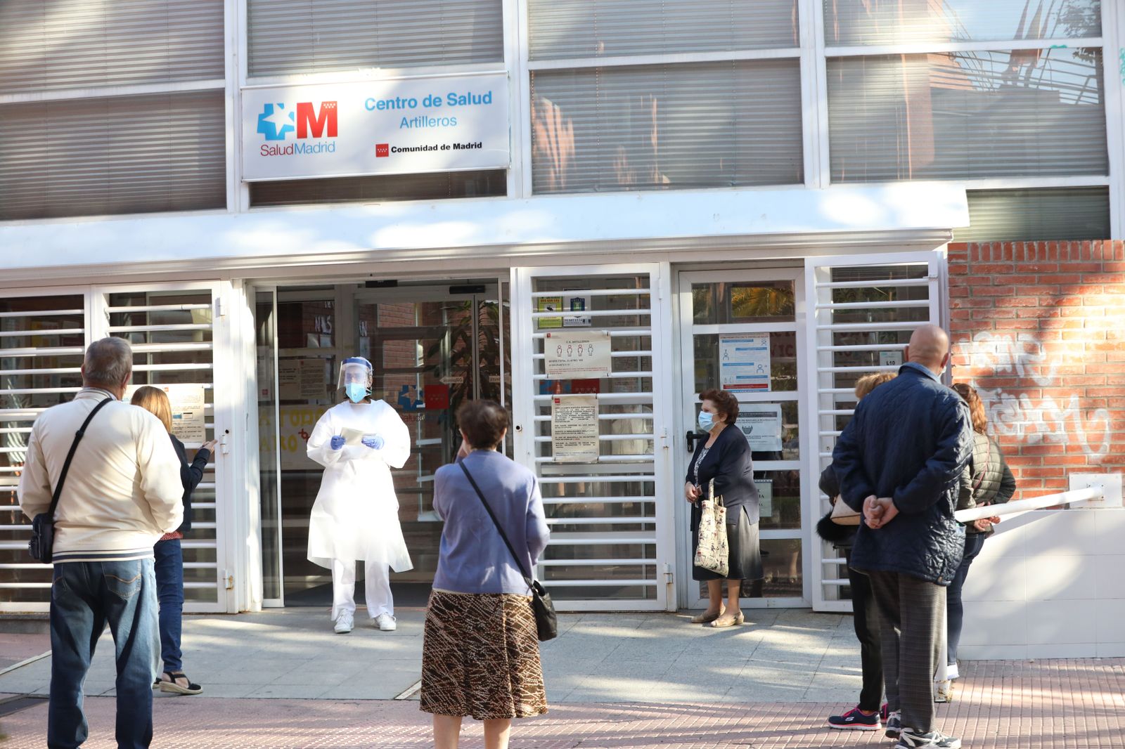 Una sanitaria sale a atender a las numerosas personas que hacen cola en un centro de salud