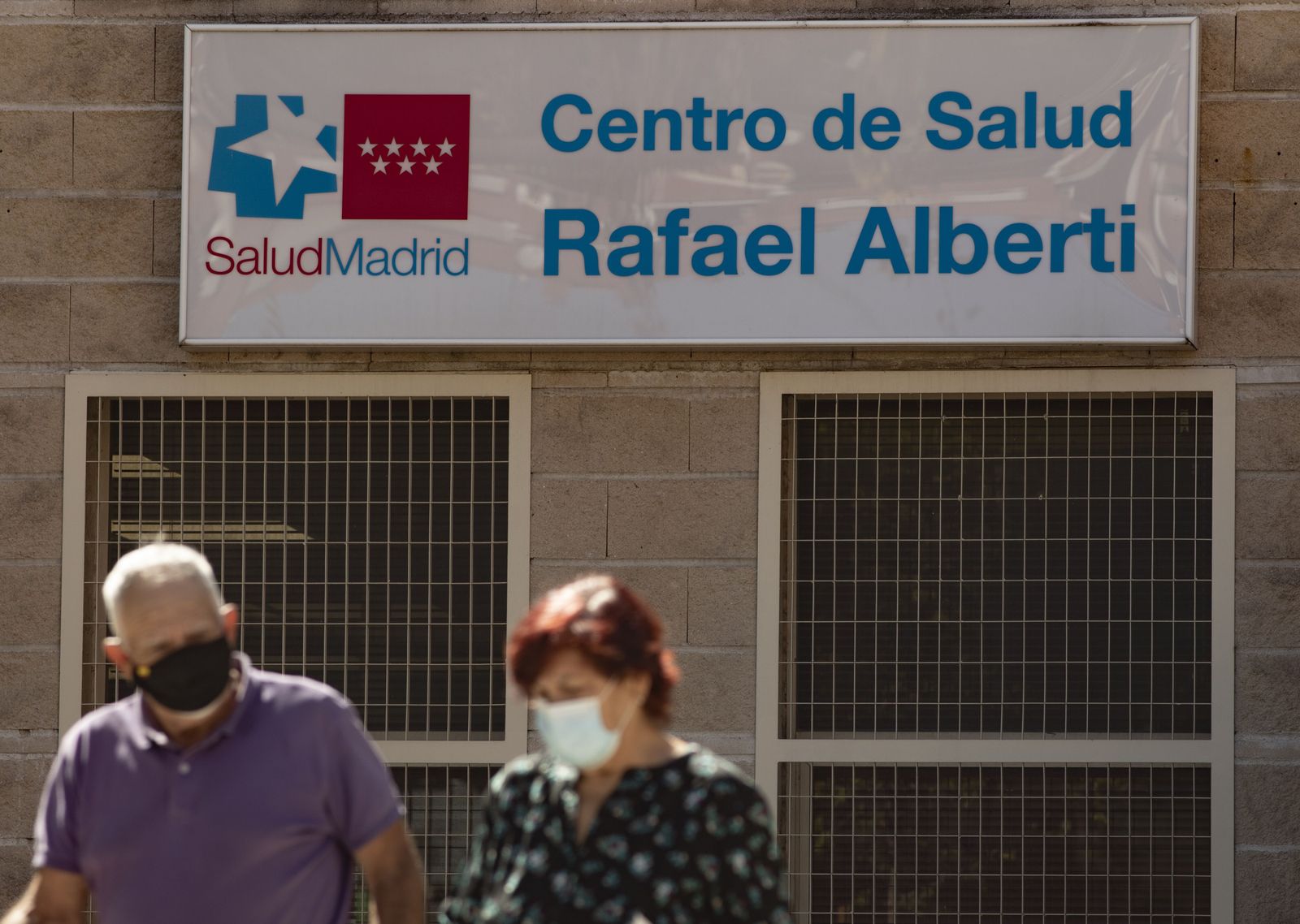 Foto recurso de dos personas caminando al lado del Centro de Salud Rafael Alberto en el distrito de Puente de Vallecas, Madrid (España).