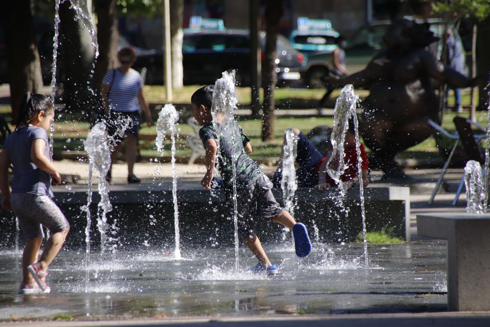 Niños jugando en la fuente del parque Alamedilla para evitar el calor