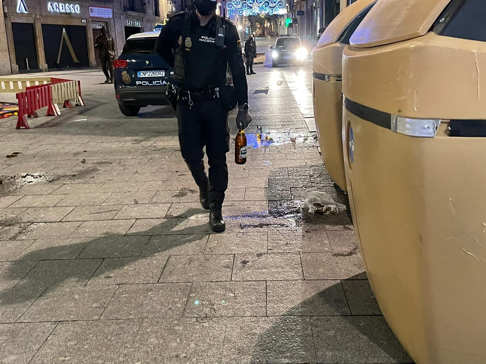 Un agente del CNP con una botella de la mano, mientras otra está rota justo detrás de él