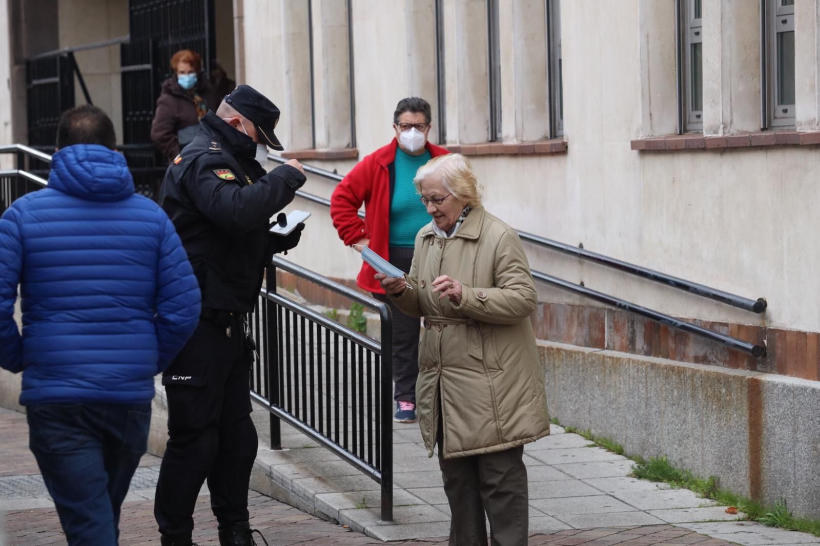 El agente de Policía Nacional entrega la mascarilla a la señora