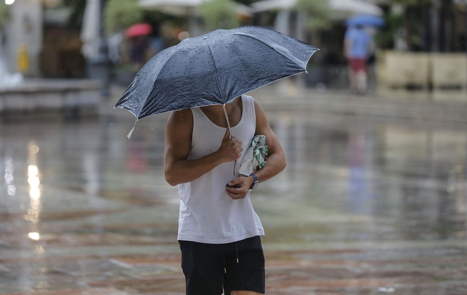 Una persona refugiada bajo un paraguas en verano. | EP Una persona refugiada bajo un paraguas en verano. | EP