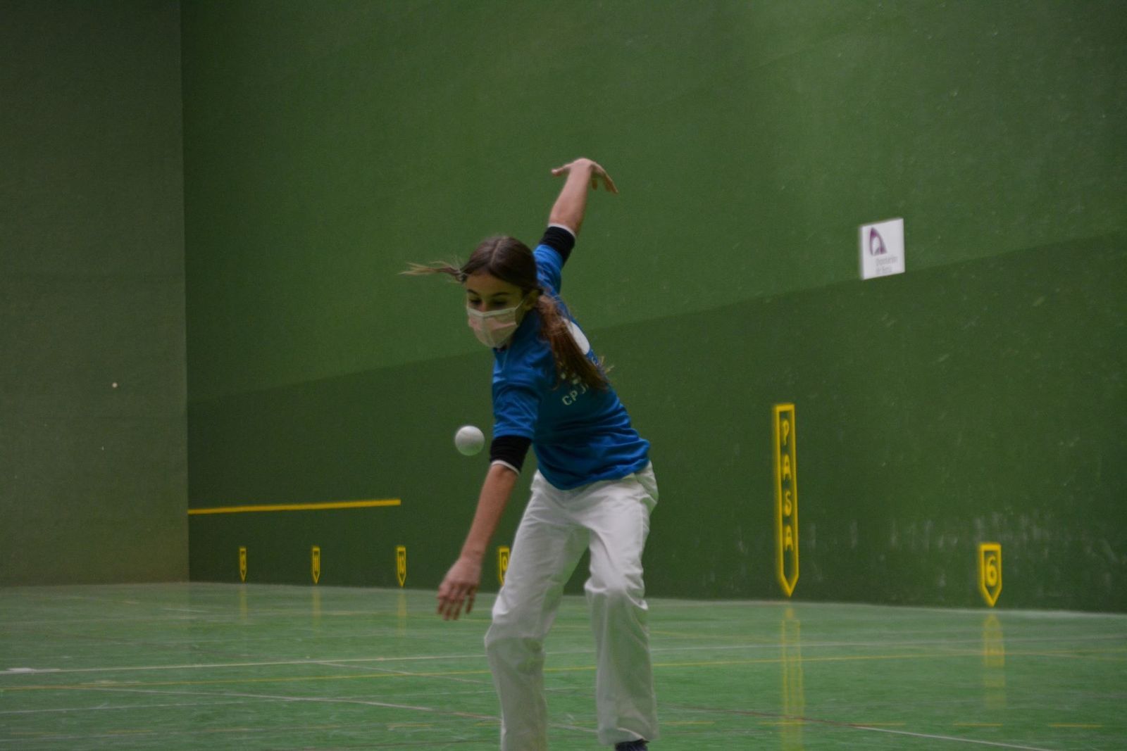 Una joven realiza un saque en Pelota a Mano.