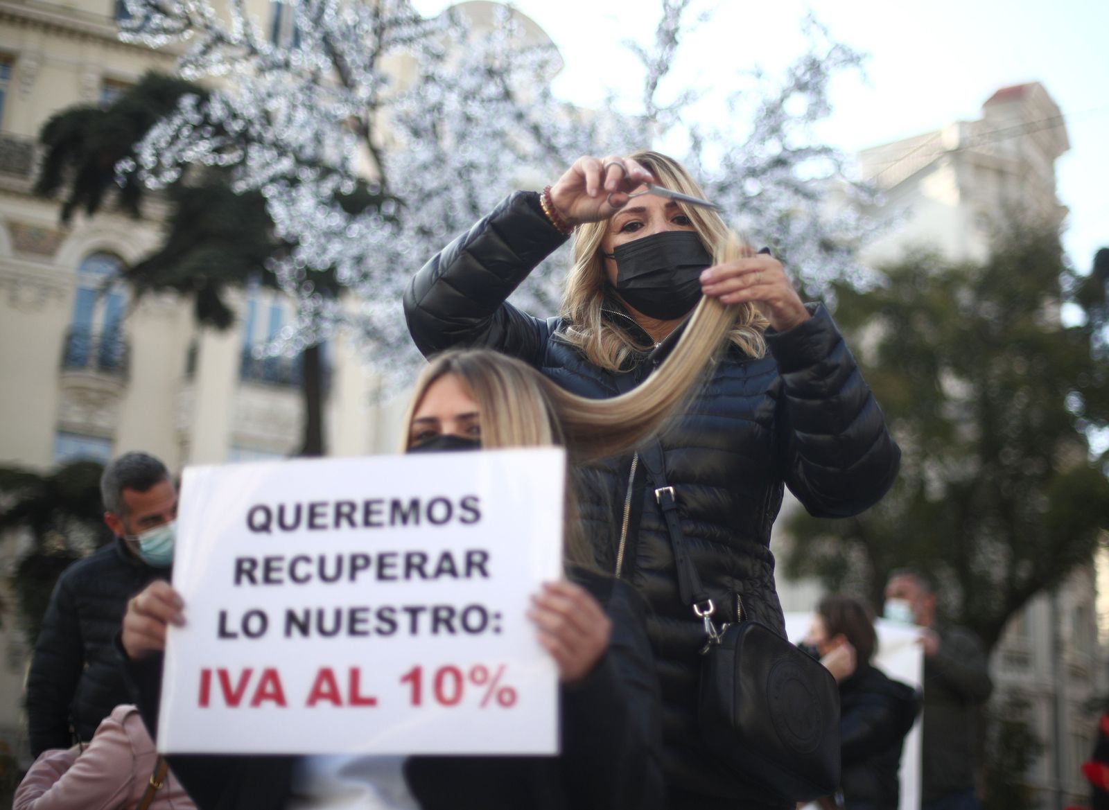 Una peluquera corta el pelo a una mujer durante una concentración frente al Congreso de los Diputados, en Madrid (España), a 17 de noviembre de 2020