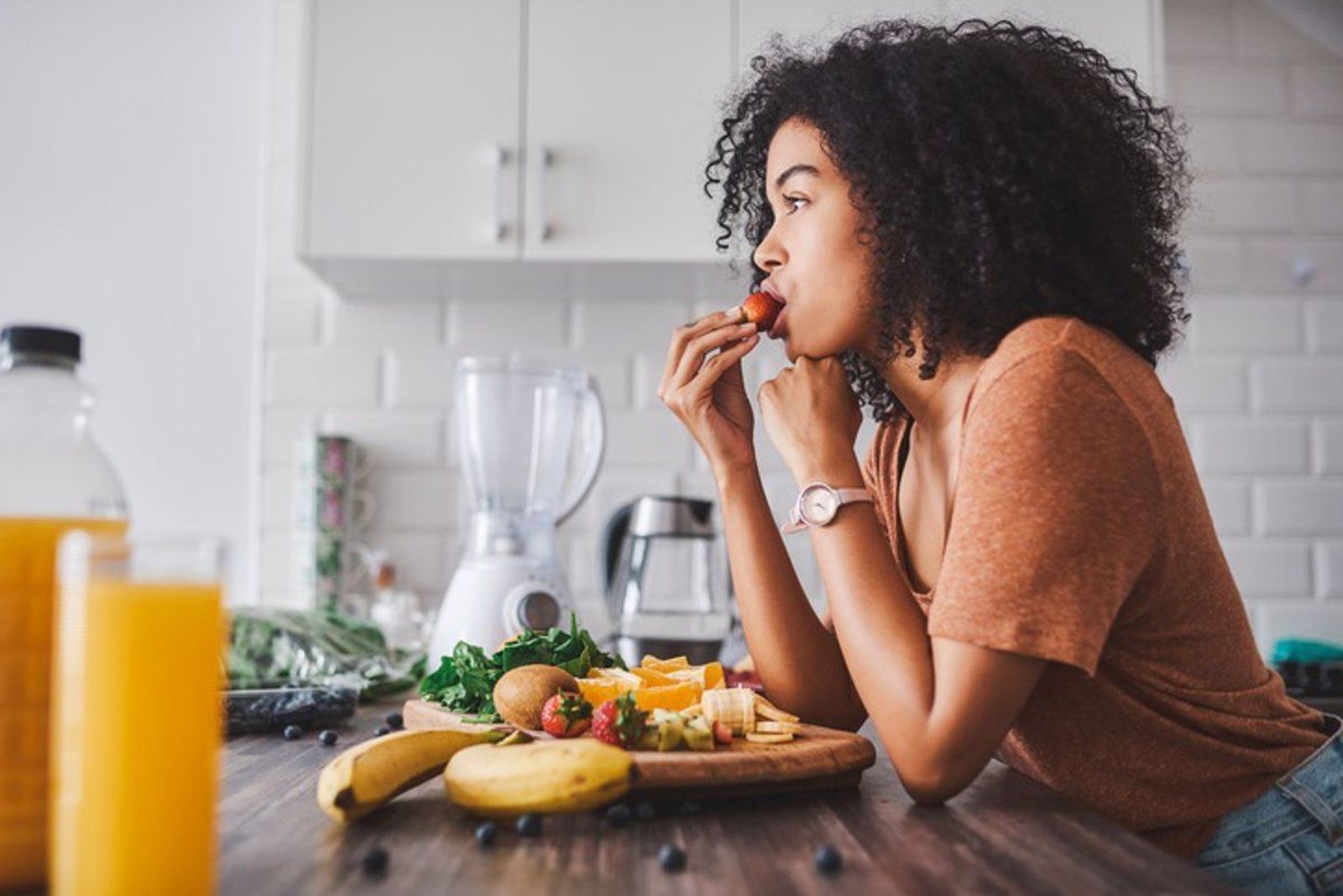 Mujer comiendo fruta en la cocina. FOTO INFOSALUS