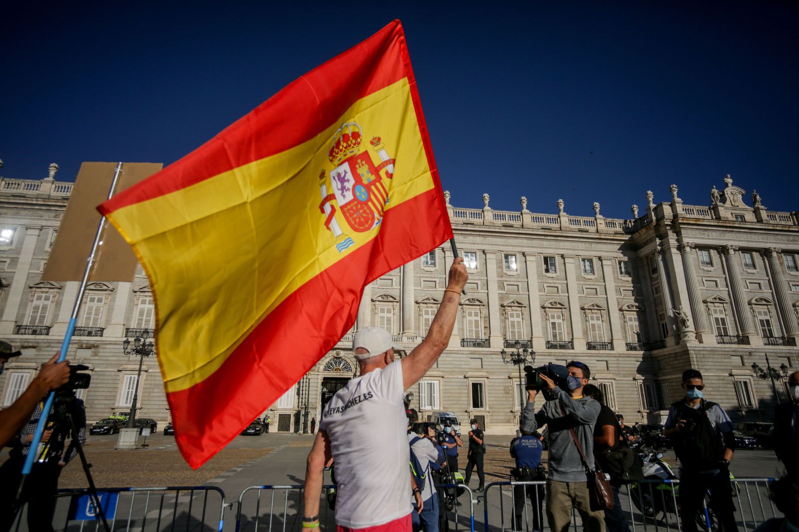 Un hombre ondea una bandera de España en el exterior del Palacio Real antes del inicio de la ceremonia de Estado para homenajear a las víctimas de la pandemia de Covid-19, celebrada en el Palacio Re