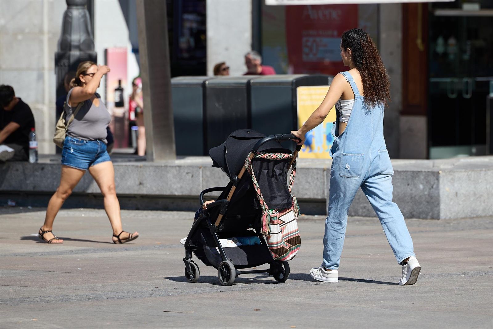 Una mujer empuja un carrito con un niño
