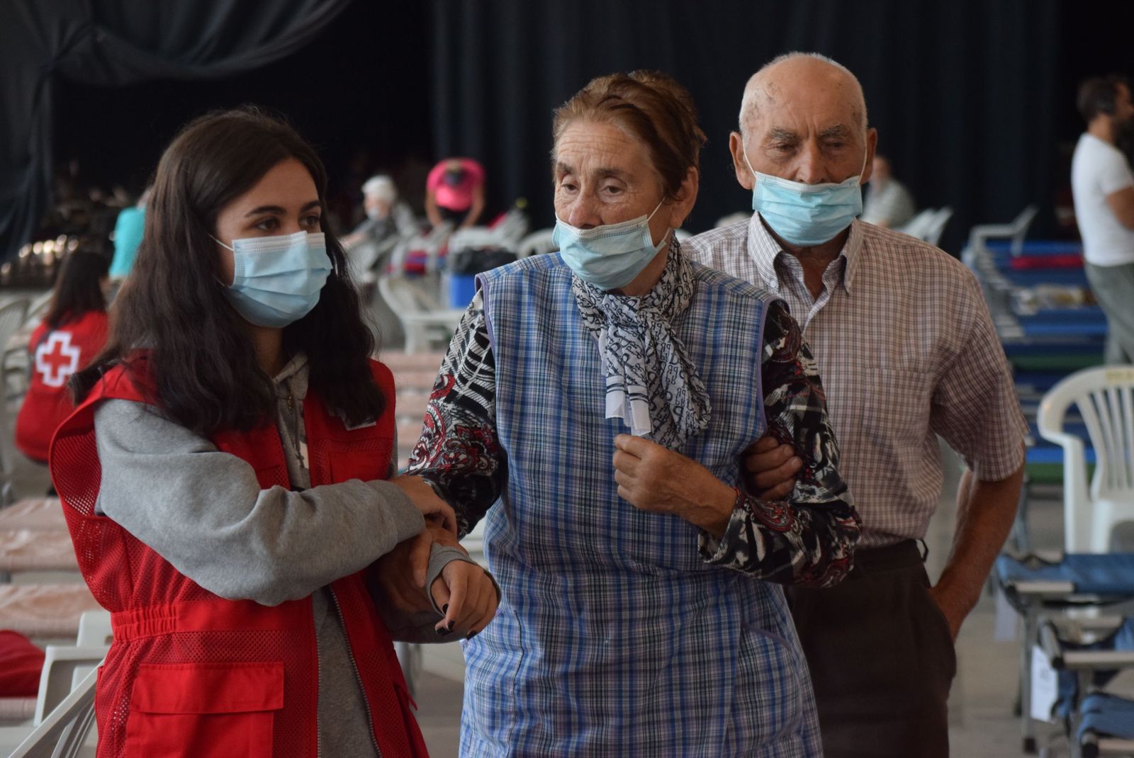 Una voluntaria de Cruz Roja ayuda a dos ancianos desalojados por el incendio en Ifeza