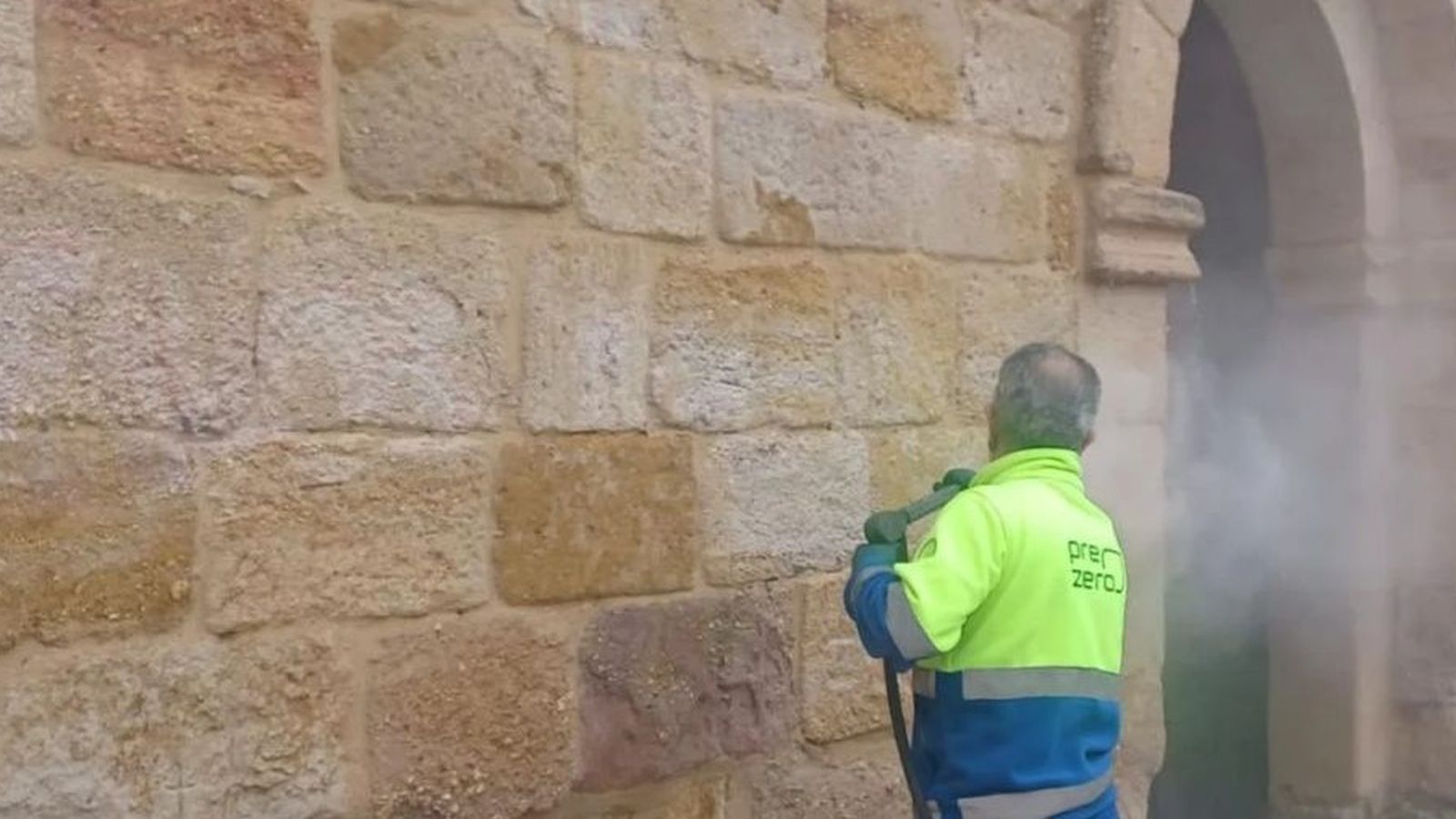 Un operario del servicio de limpieza retirando la pintada