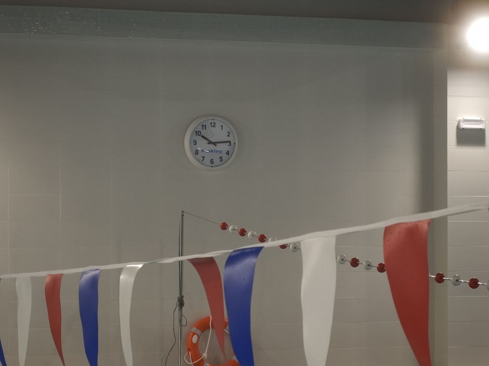 Banderines y nuevo reloj en la piscina de La Alamedilla