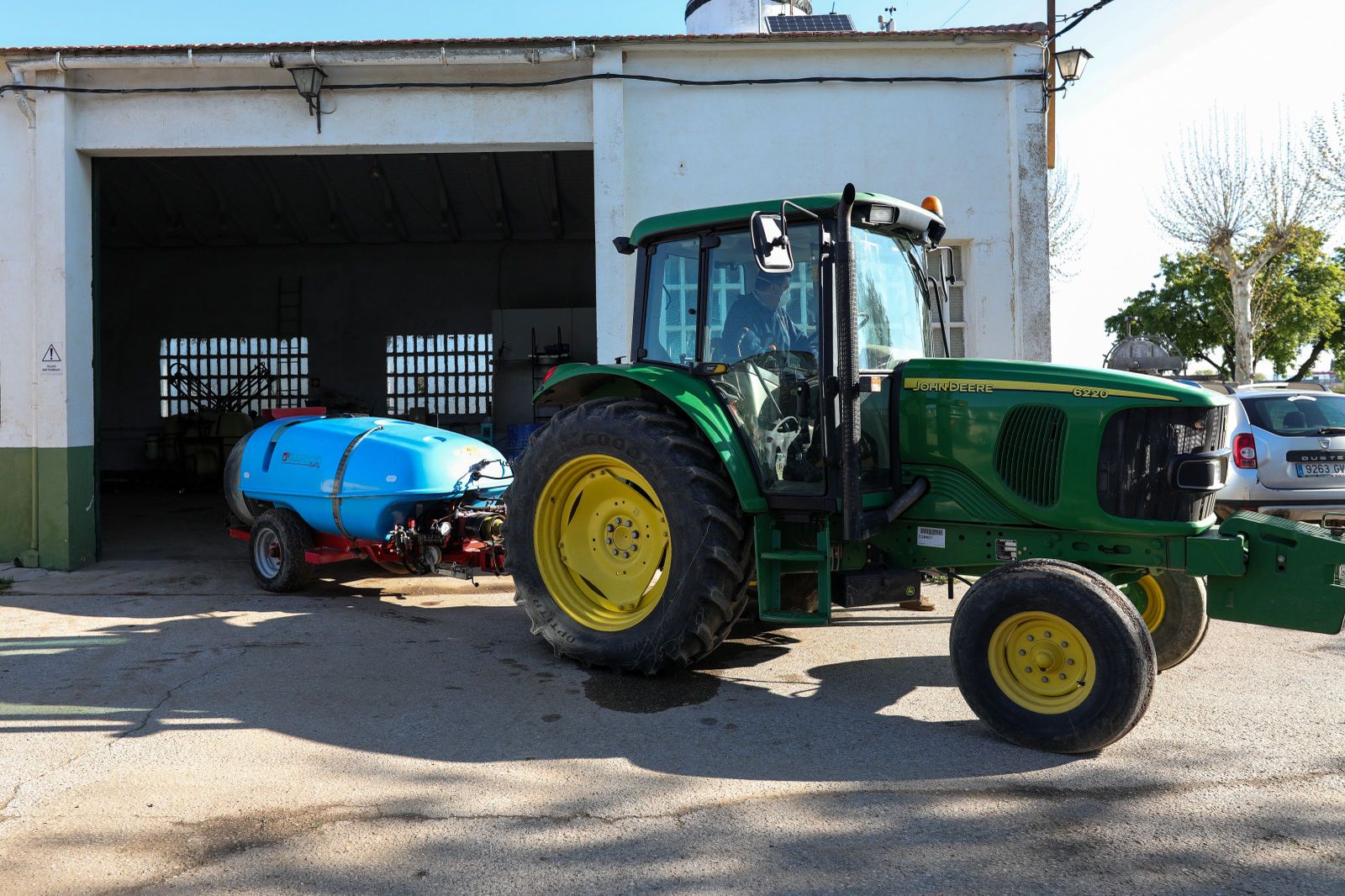 Un agricultor montado en su tractor saliendo de una nave. Foto EP