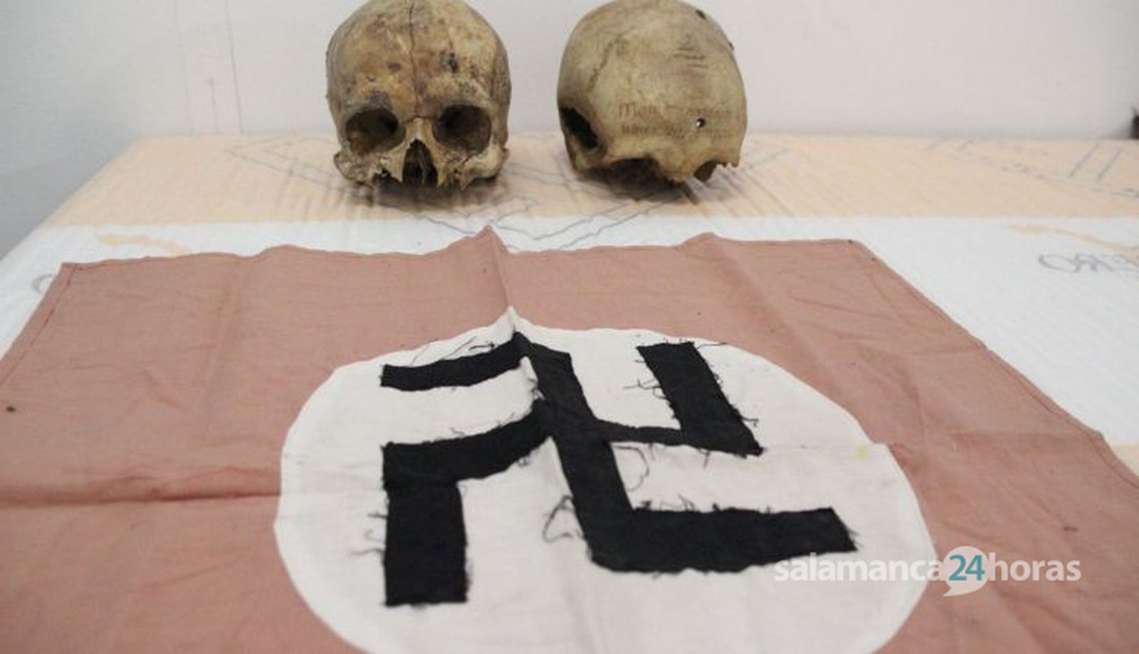 Dos calaveras humanas con agujeros de bala del S. XVII junto a una bandera nazi. Patrimonio almacenado en una nave