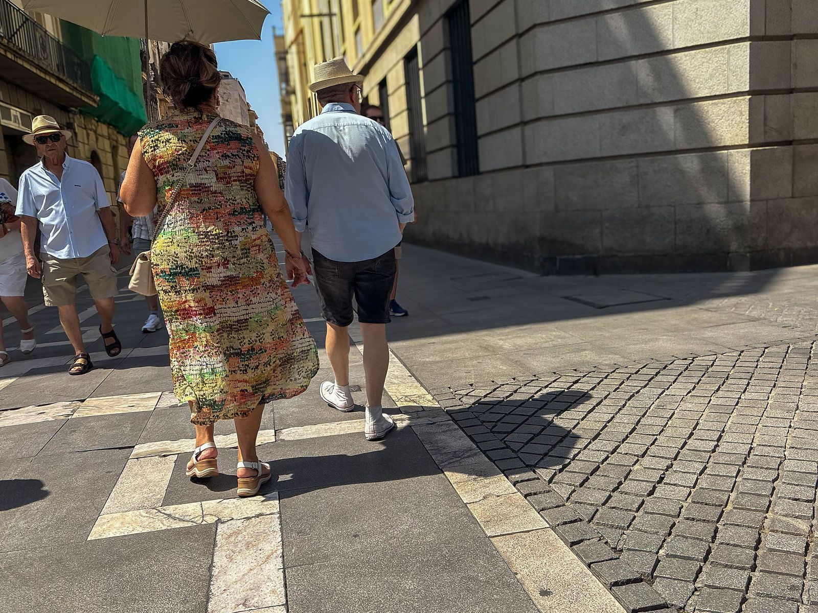 Una mujer pasea por la calle Santa Clara bajo un paraguas por el intenso calor