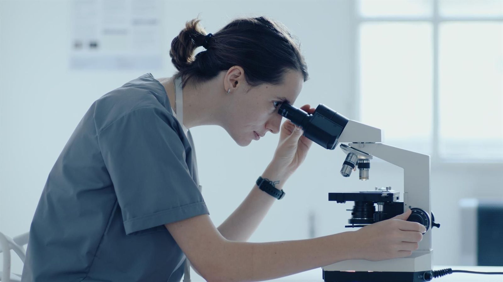 Investigadora mirando por un microscopio   MICIU   Archivo
