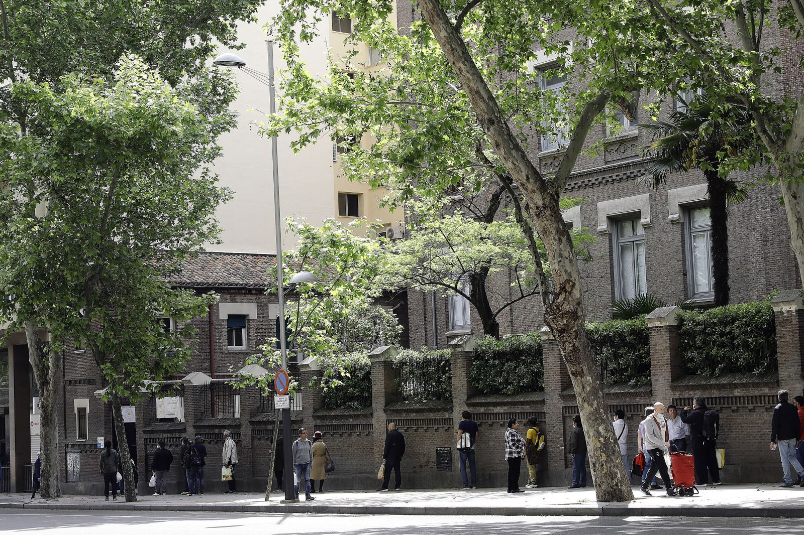 Decenas de personas esperan en la cola a las puertas del Comedor Social María Inmaculada de la capital para recoger alimentos.