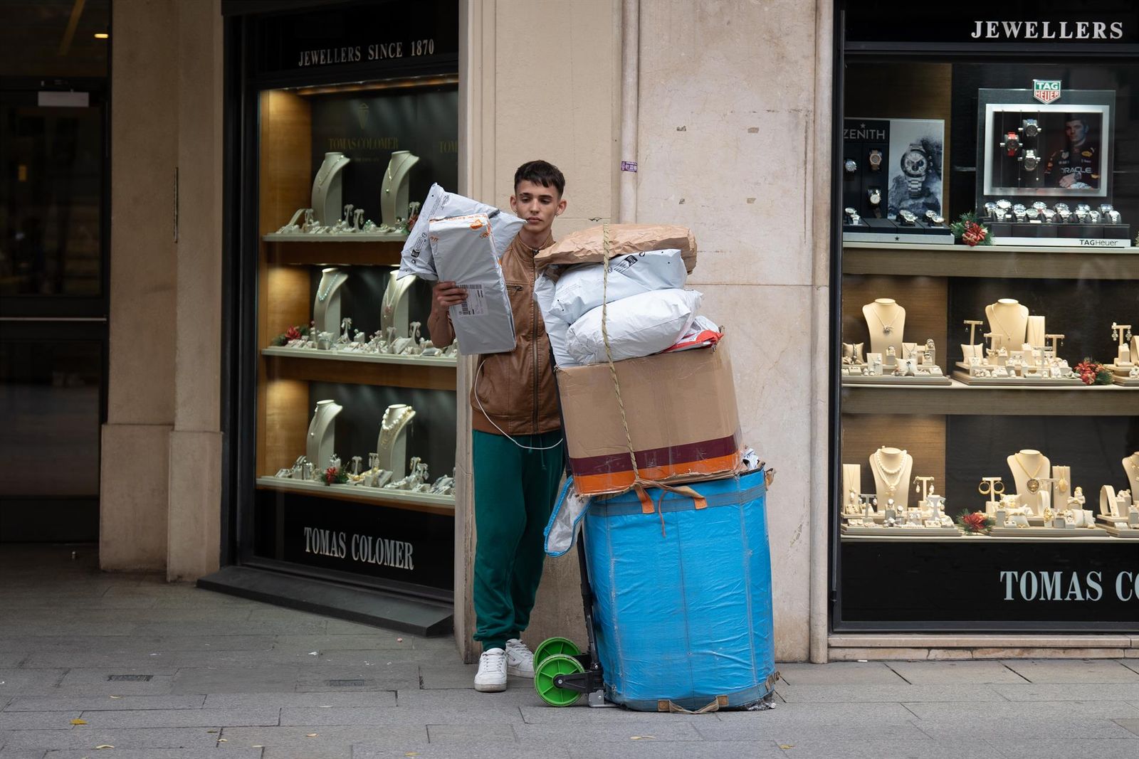 Un joven repartidor se apoya junto a cajas con compras durante la campaña de Navidad - David Zorrakino - Europa Press - Archivo