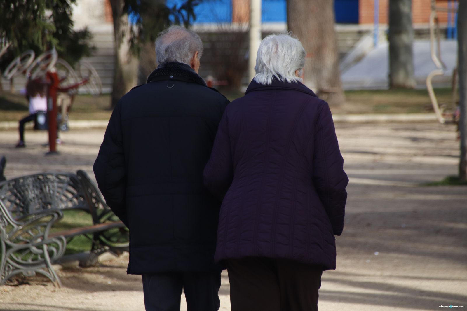 Dos personas mayores paseando por la Plaza de España