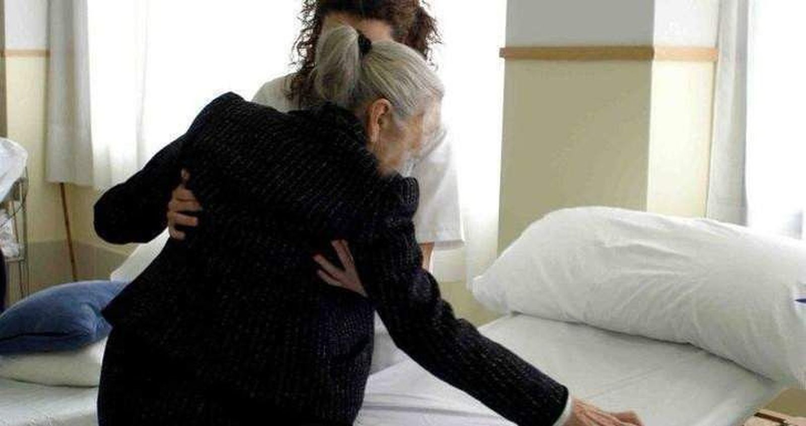 Una mujer ayuda a otra a levantarse de la cama Una mujer ayuda a otra a levantarse de la cama