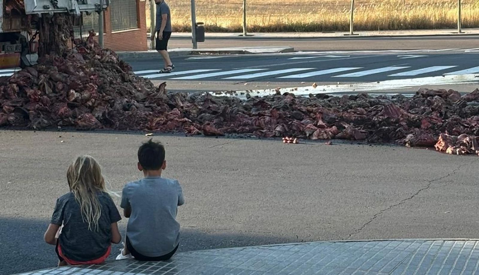 Dos niños miran el suceso ocurrido en Salamanca tras abrirse la puerta trasera de un camión
