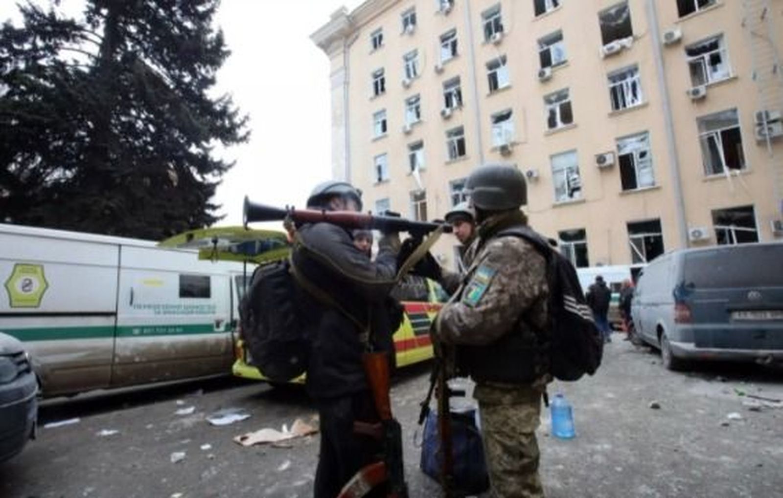 Soldiers and locals stand with weapons outside the building of Kharkiv city hall after a shelling by Russian troops. Photo  Ukrinformdpa