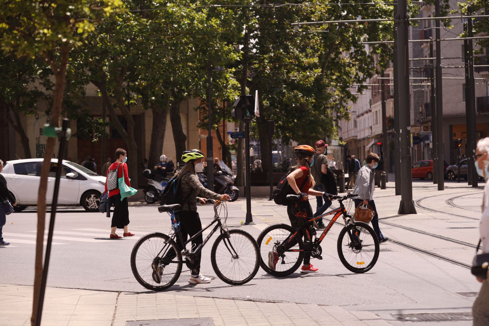 Jóvenes con mascarilla pasean con bicicleta